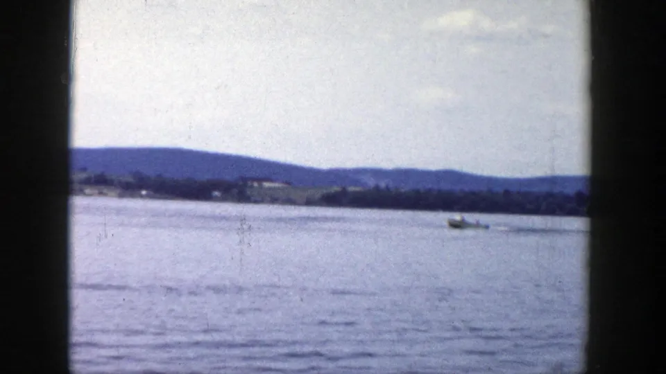 1958 Wisconsin lake view with a small boat far across the water, distant hills, and visible 8mm gate borders.
