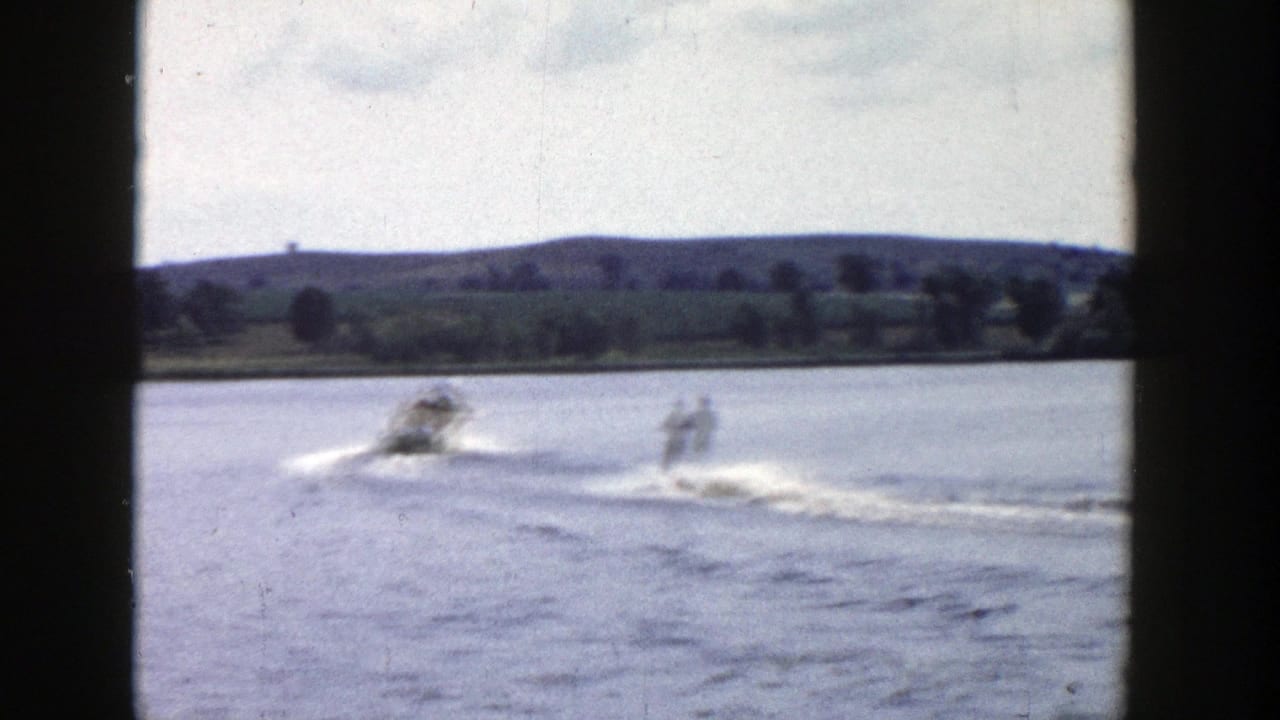 Soft 8mm frame of a Wisconsin water-skiing pass, with boat and skier blurred by motion.