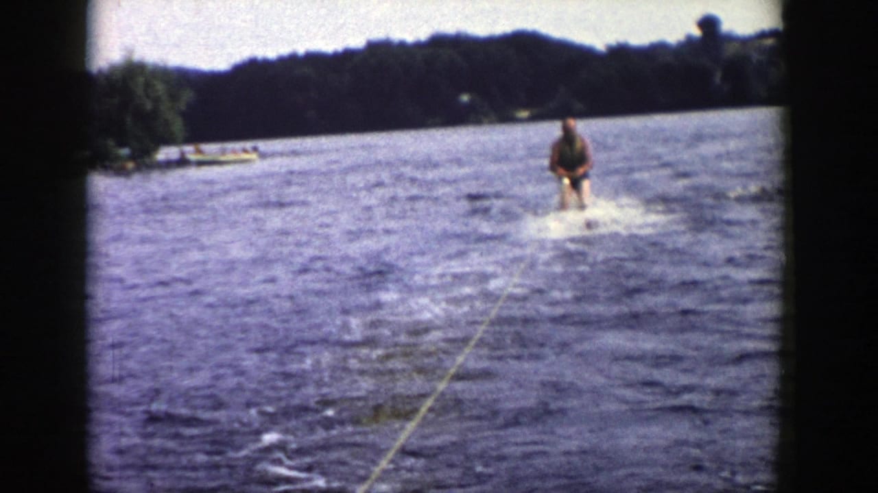 The skier remains upright behind the boat, holding the rope as the lake and distant Wisconsin shoreline fill the frame.