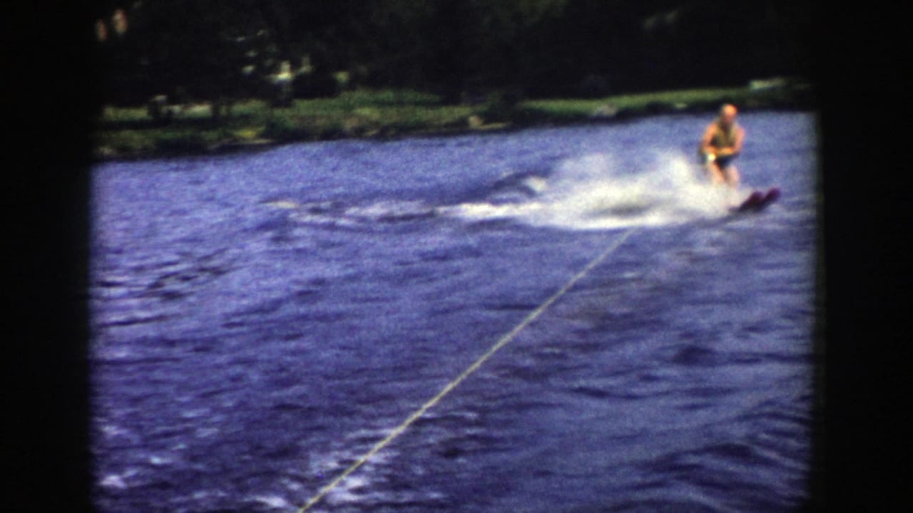 The 1958 Wisconsin lake footage shows the man water skiing closer to frame center, leaning over choppy water with spray behind him.
