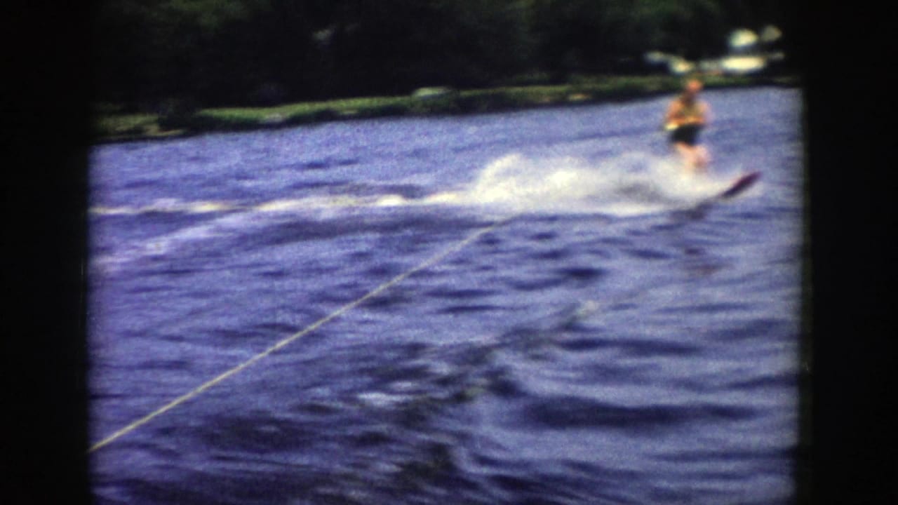 A final 1958 Wisconsin frame shows the skier pulled across the lake, partly softened by motion blur, with rope, spray, and shoreline visible.