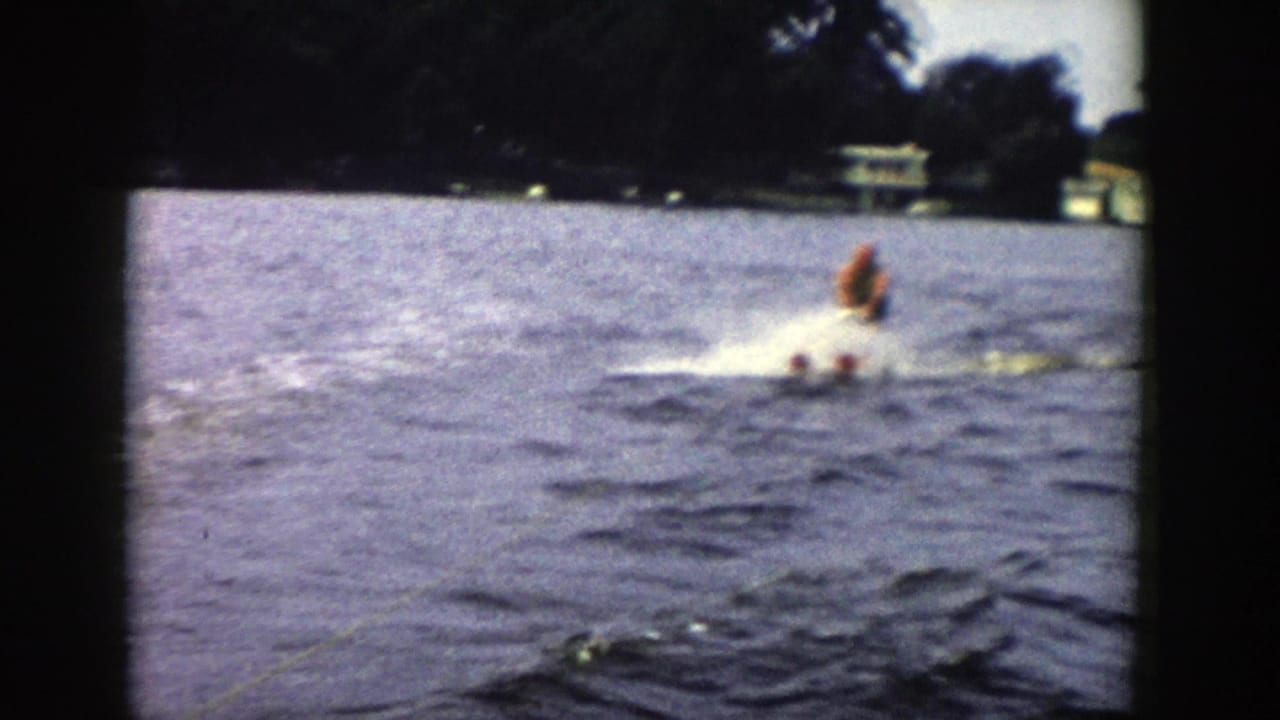 The skier continues across the Wisconsin lake, partly softened by motion and 8mm grain as spray breaks around his skis.