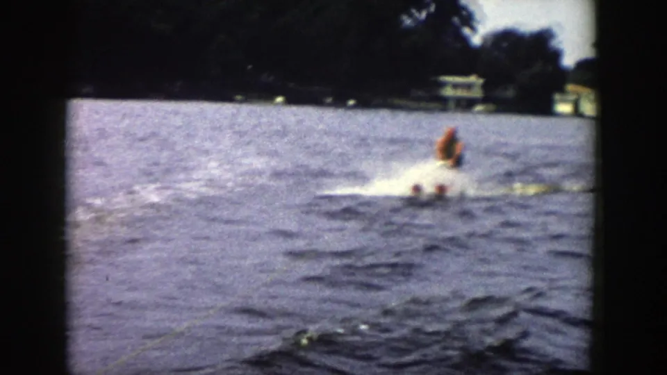 The skier continues across the Wisconsin lake, partly softened by motion and 8mm grain as spray breaks around his skis.