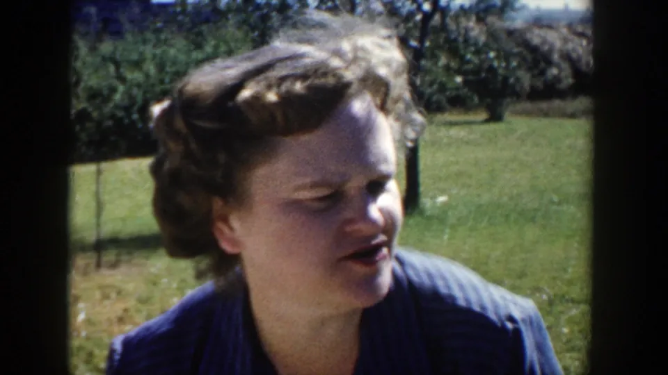 The second woman turns in profile, appearing to speak in the 1958 Wisconsin outdoor home-movie gathering.