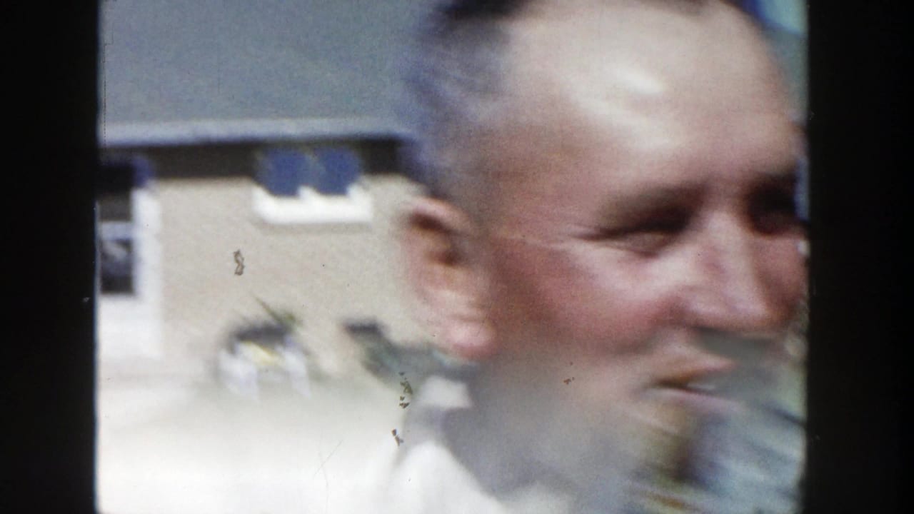 The man appears in soft motion blur while turning in the Wisconsin backyard, with the house and lawn still visible behind him.