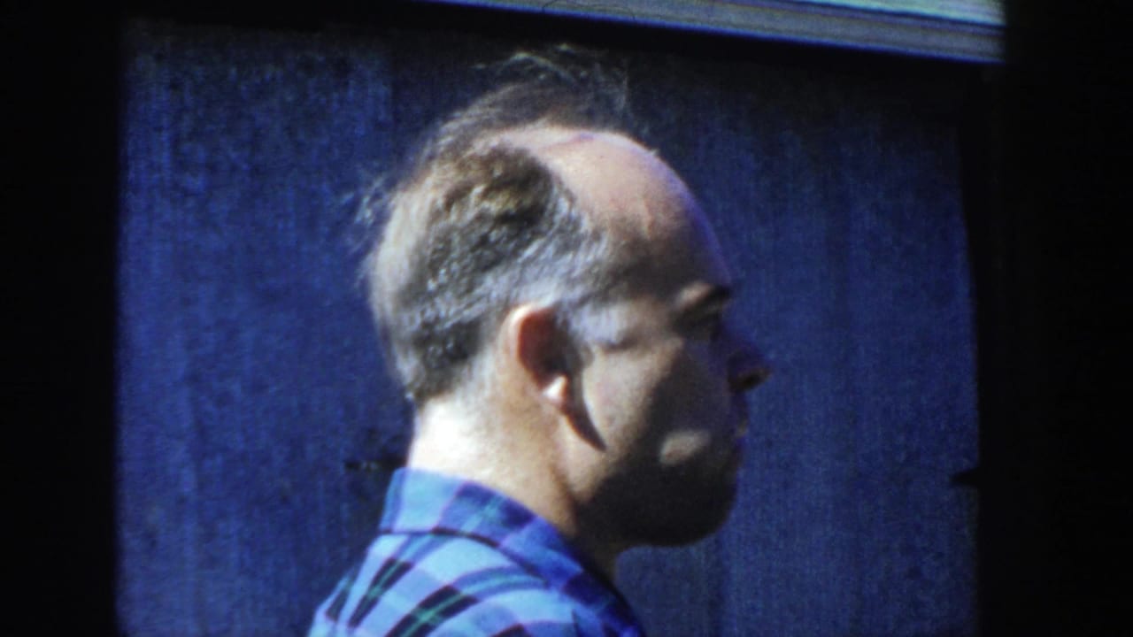 A second adult man in a blue plaid shirt appears in side profile against a dark background at the end of the clip.