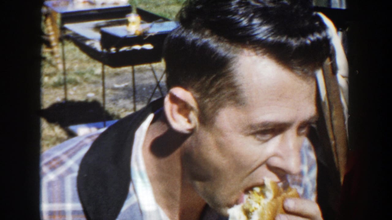 The 1958 Wisconsin picnic footage shows a young man biting a burger, with folding chairs and a small table behind him.