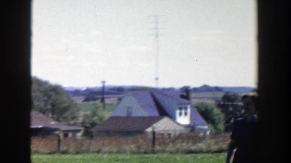 1958 Wisconsin rural landscape with houses, fields, trees, and a utility pole viewed through a dark window frame.