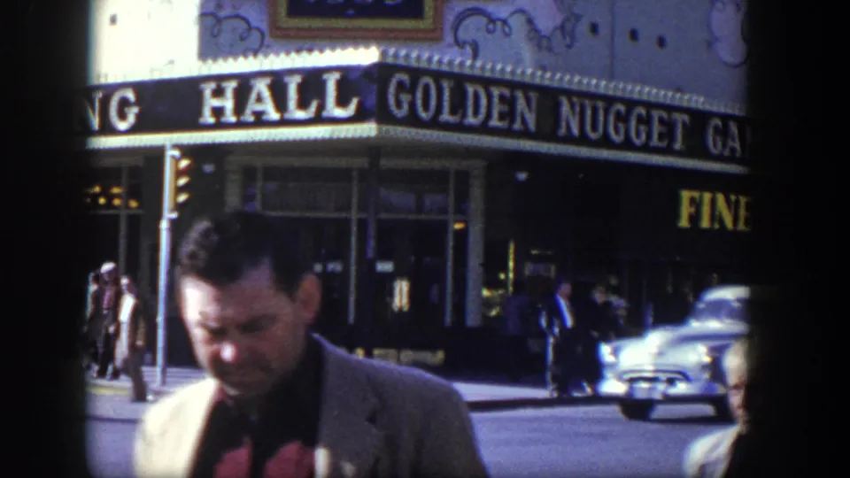 1954 Las Vegas street view with a suited man near the Golden Nugget Gambling Hall exterior and mid-century traffic behind him.