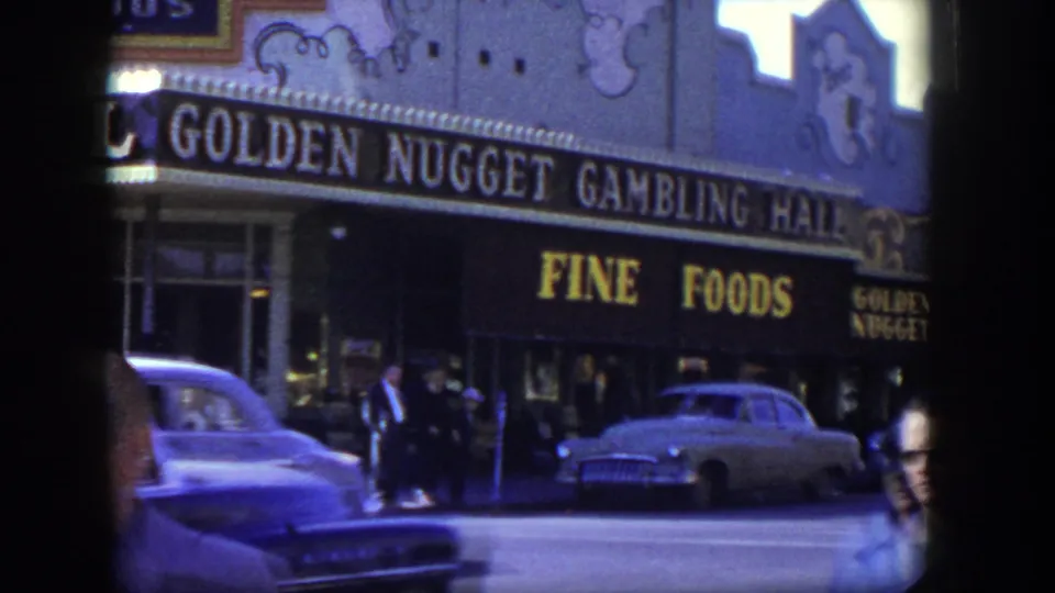 Golden Nugget Gambling Hall exterior in Las Vegas, 1954, with pedestrians on the sidewalk and mid-century cars moving past.