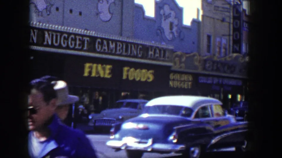 1954 Las Vegas sidewalk scene with men in hats near the Golden Nugget exterior and a two-tone car passing in front.