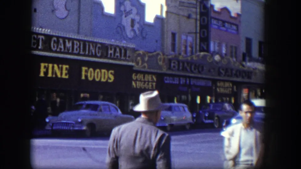 Las Vegas Golden Nugget exterior in 1954 with a fedora-wearing man in the foreground, visible casino signage, and parked or passing cars.