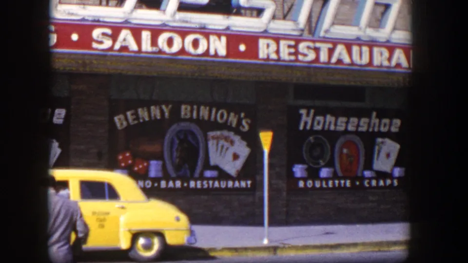 1954 Las Vegas street scene showing a suited man near a yellow taxi outside Benny Binion's Horseshoe signage.