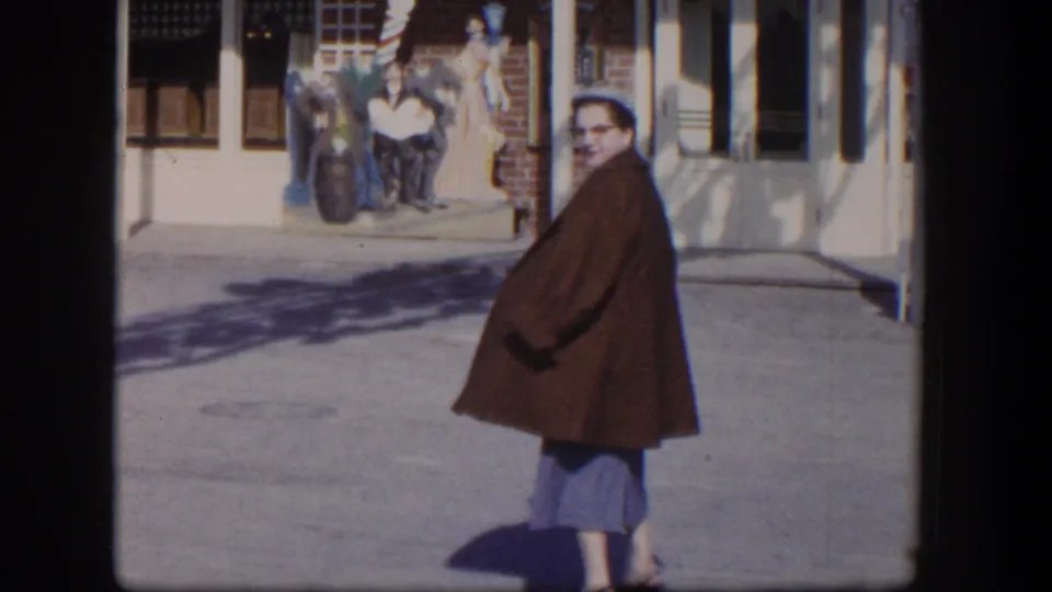 1954 Las Vegas street view with a woman in a brown coat turning near the sidewalk and Horseshoe signage visible behind her.