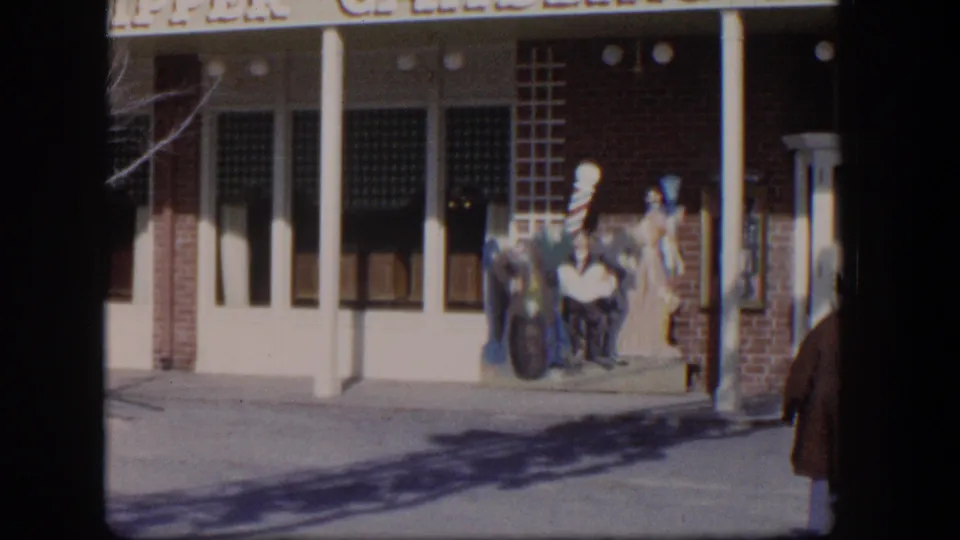 1954 Las Vegas view of the Clipper Gambling Hall exterior with brick walls, white columns, sidewalk, and display figures by the doorway.