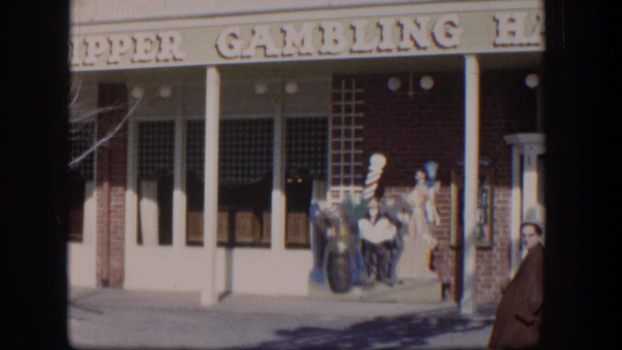 Storefront sign and columns with a person in a red coat entering the right edge of the frame.