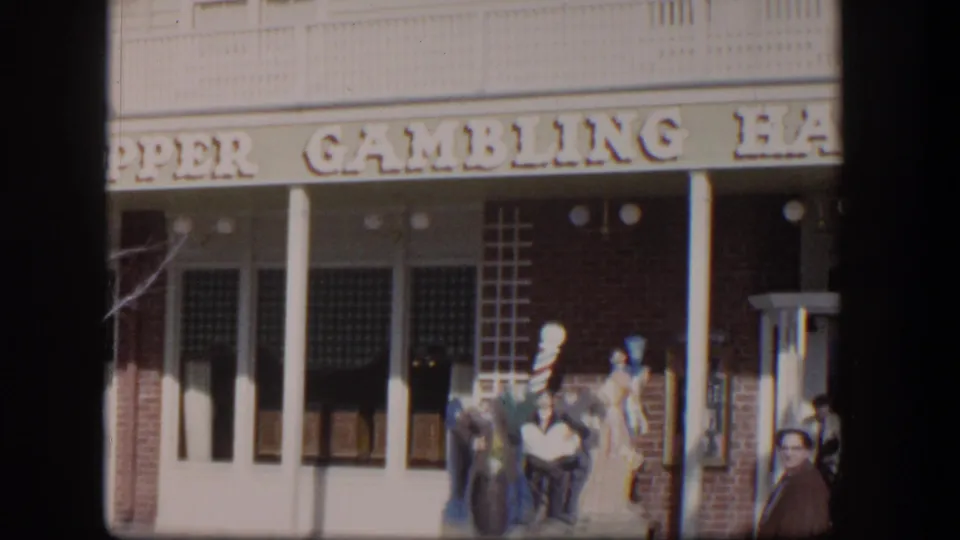 Las Vegas gambling hall exterior in 1954 with the sign partly cropped, white columns, storefront windows, and a pedestrian at the lower right.