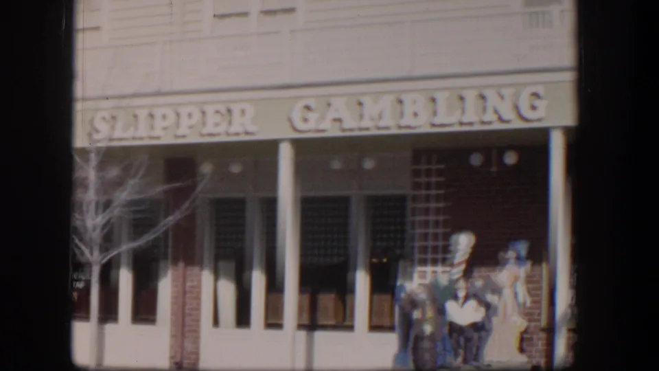 1954 Las Vegas exterior of the Clipper Gambling Hall showing the sign, white columns, bare branches, and painted or mannequin figures near the entrance.