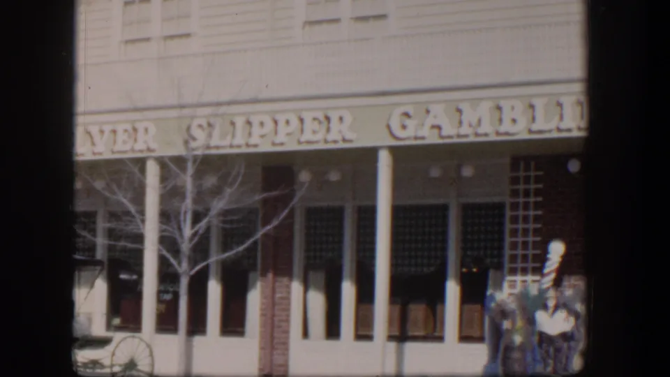 1954 Las Vegas home-movie frame showing the Silver Slipper Gambling exterior, white columns, dark windows, and people near the entrance.