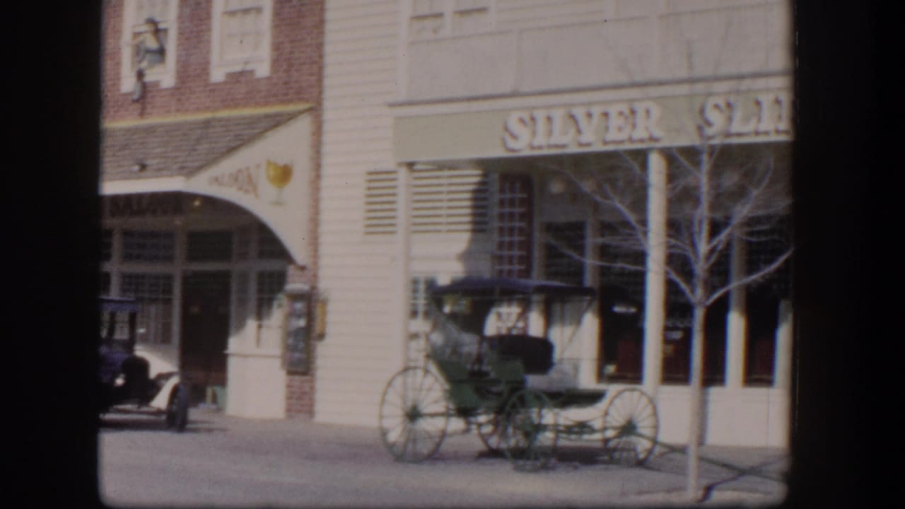 1954 Las Vegas street view showing Silver Slipper signage, a saloon facade, parked carriage, sidewalk, windows, and a bare tree.