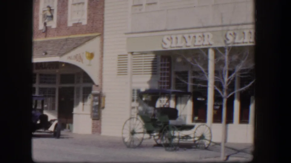 1954 Las Vegas street view showing Silver Slipper signage, a saloon facade, parked carriage, sidewalk, windows, and a bare tree.