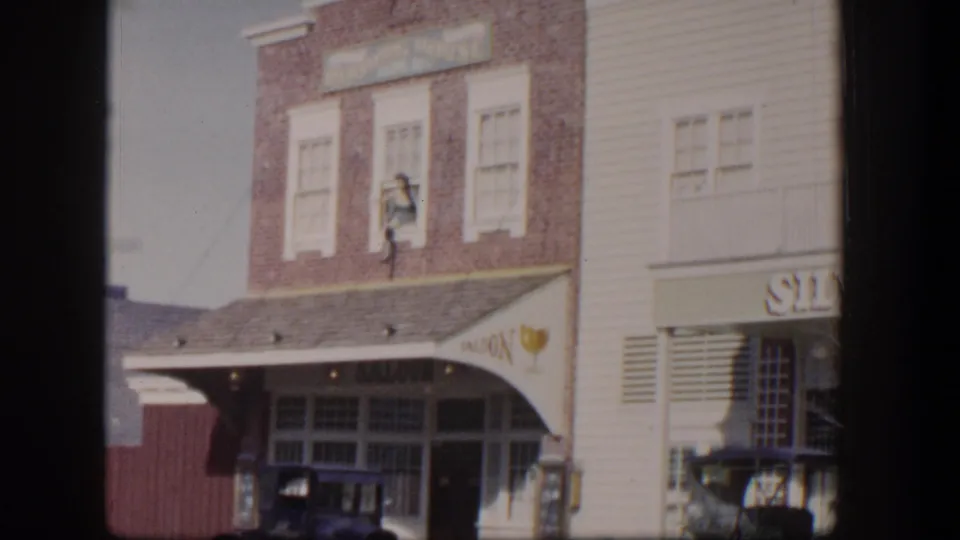 1954 Las Vegas frame showing the saloon-style facade, early automobile, carriage, upper brick windows, and partial Silver Slipper signage.