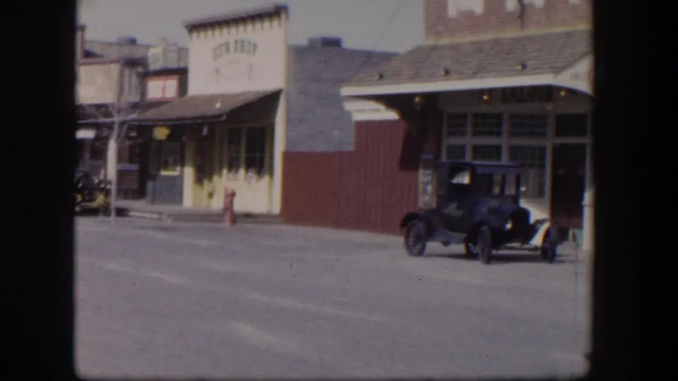 1954 Las Vegas street scene showing storefront signage, a red hydrant, and an early automobile near the curb.