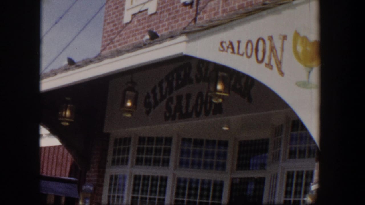 1954 Las Vegas home-movie frame showing the Silver Saloon awning, beer-glass graphic, brick facade, and a parked older car.