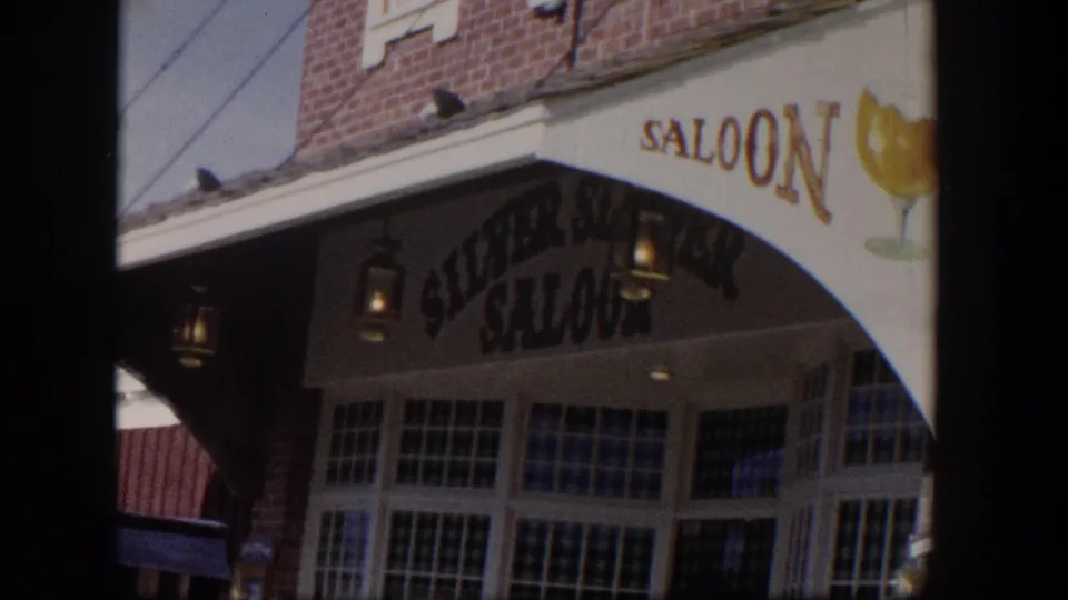 1954 Las Vegas home-movie frame showing the Silver Saloon awning, beer-glass graphic, brick facade, and a parked older car.