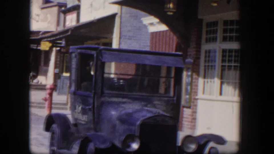 1954 Las Vegas frame showing a dark older automobile parked in front of the Silver Saloon facade and windows.