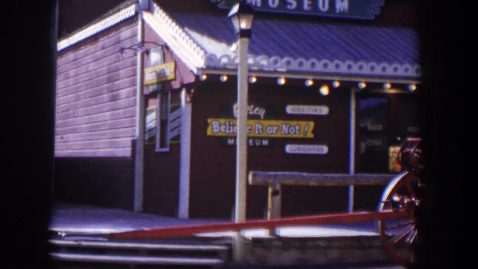 1954 Las Vegas 8mm frame showing a Believe It or Not museum facade, porch railing, hanging signs, and part of a red fire engine.