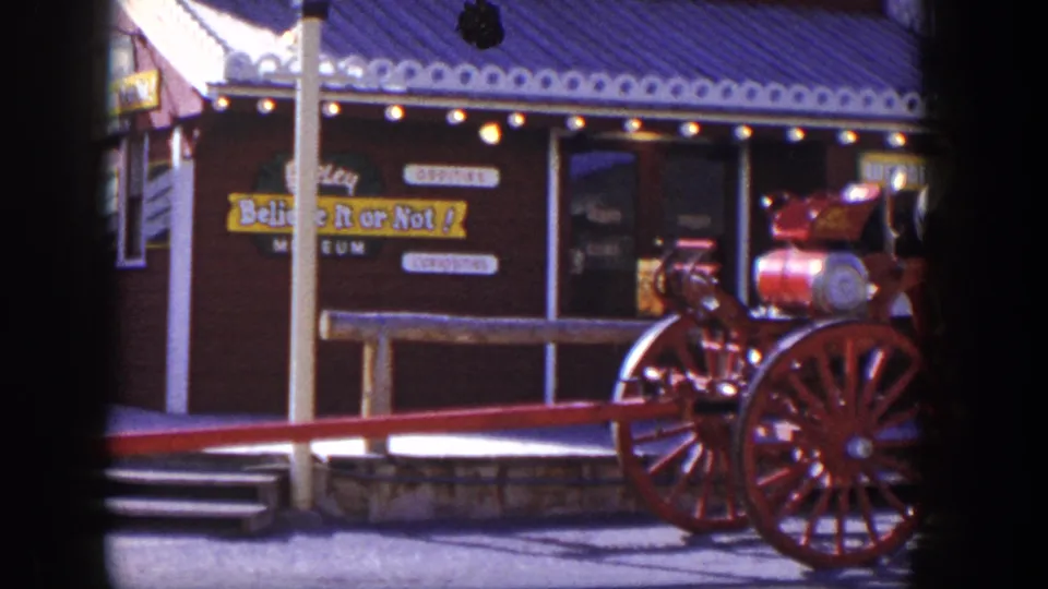 1954 Las Vegas frame showing the Believe It or Not museum frontage and a vintage red fire engine display near the sidewalk.