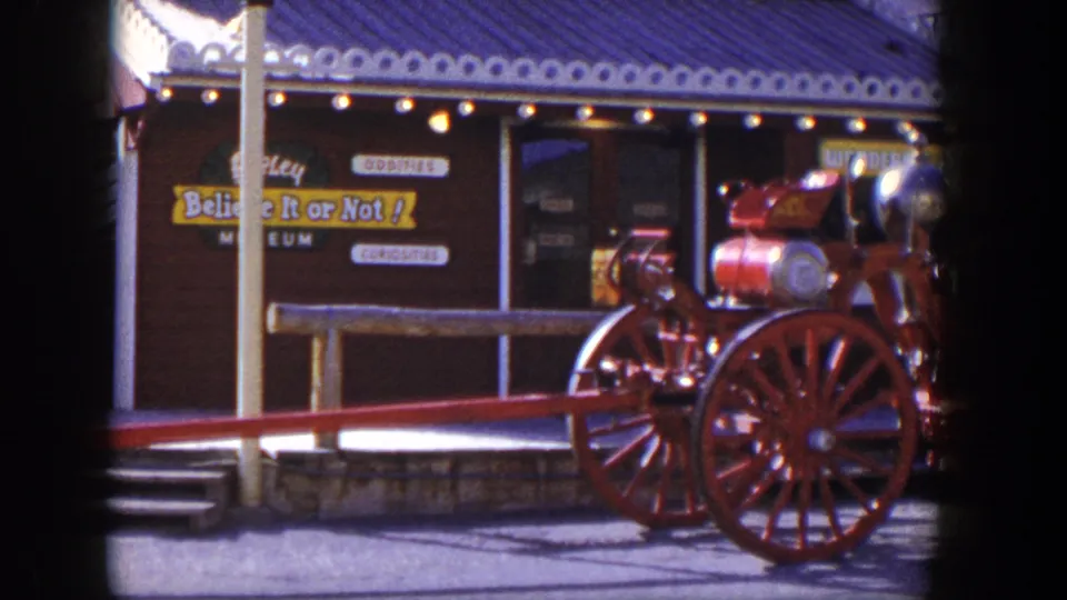 1954 Las Vegas home-movie frame showing a red antique steam fire engine parked before Believe It or Not! signage.