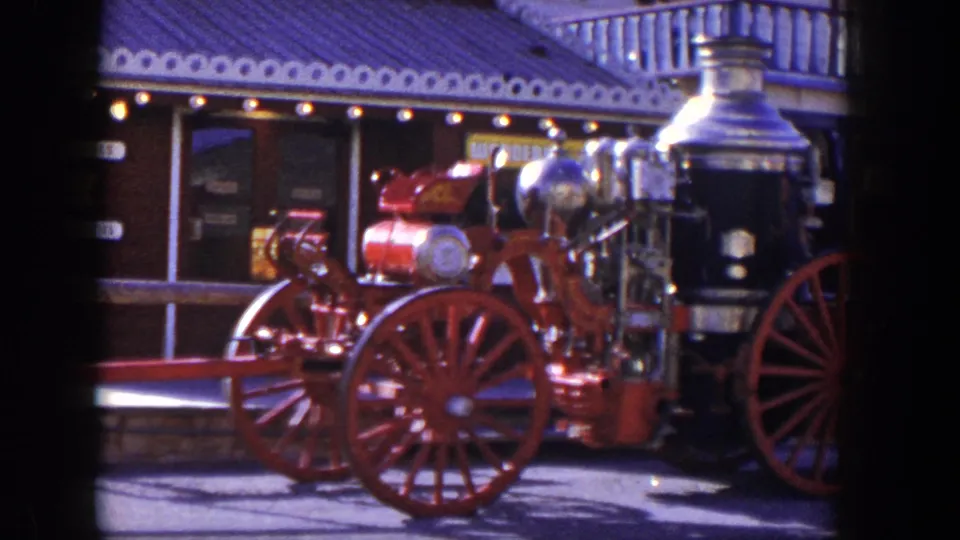 Closer 1954 Las Vegas frame of the steam fire engine, showing red wheels, polished metal parts, and the museum exterior.