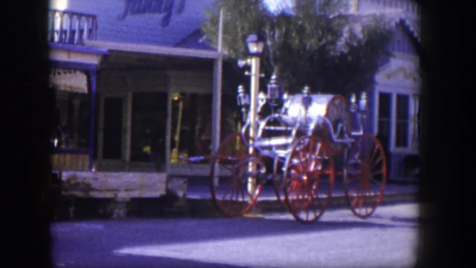 1954 Las Vegas street view with a polished vintage fire engine, red wheels, storefront facade, and streetlamp.