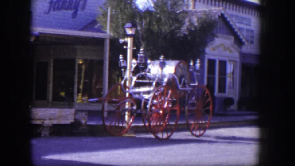 1954 Las Vegas frame with the vintage fire apparatus centered against storefront windows and mid-century street details.