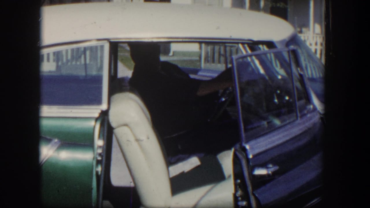 Two-tone 1950s car with open door and cream front seat visible.