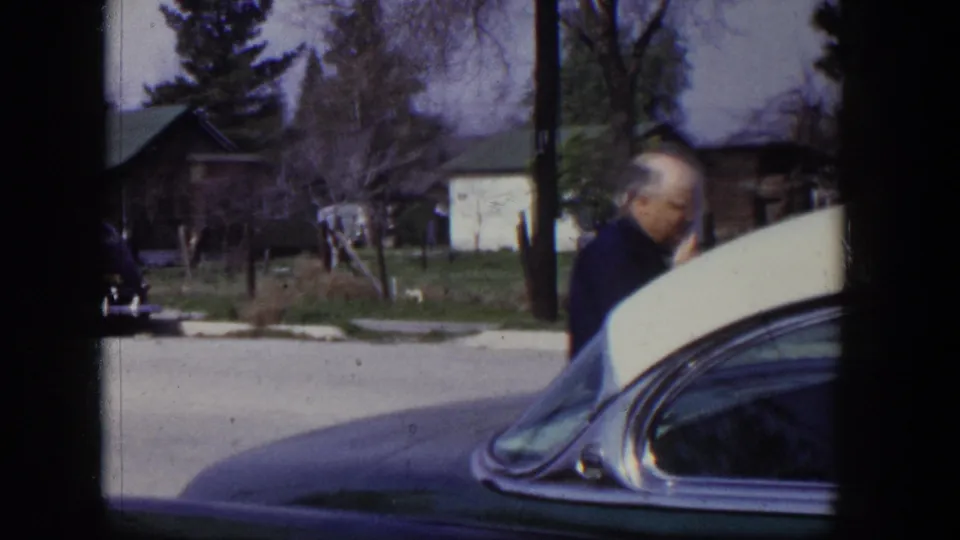 A suited middle-aged man stands near the two-tone car in a Las Vegas residential neighborhood in 1954.