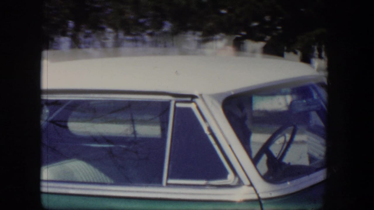 Close view of a green and white sedan side window and roofline.