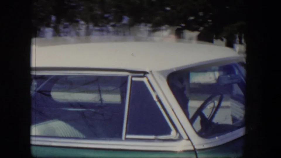 1954 Las Vegas home-movie frame showing the side windows, white roof, and green body of a parked mid-century sedan.