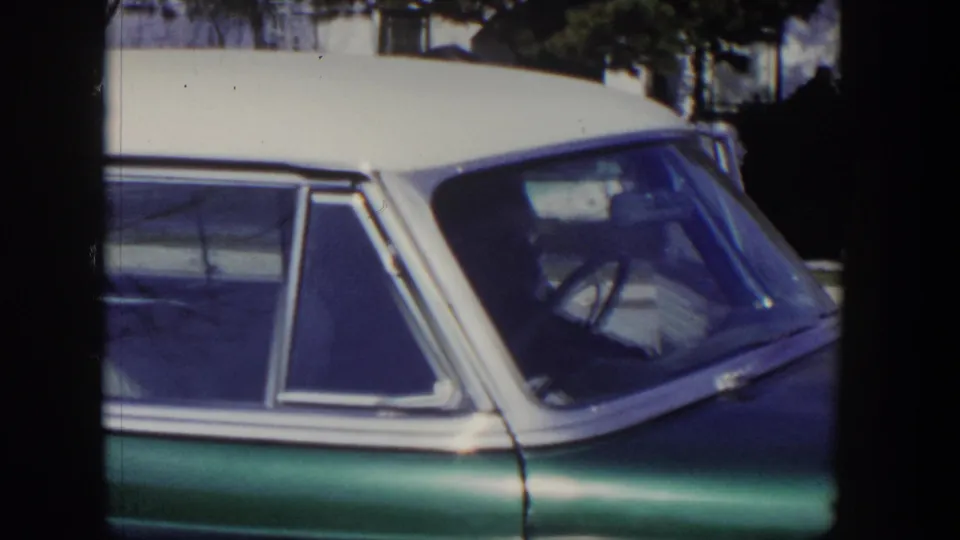 1954 Las Vegas 8mm frame showing a parked green and white sedan with chrome trim, side glass, and steering wheel.
