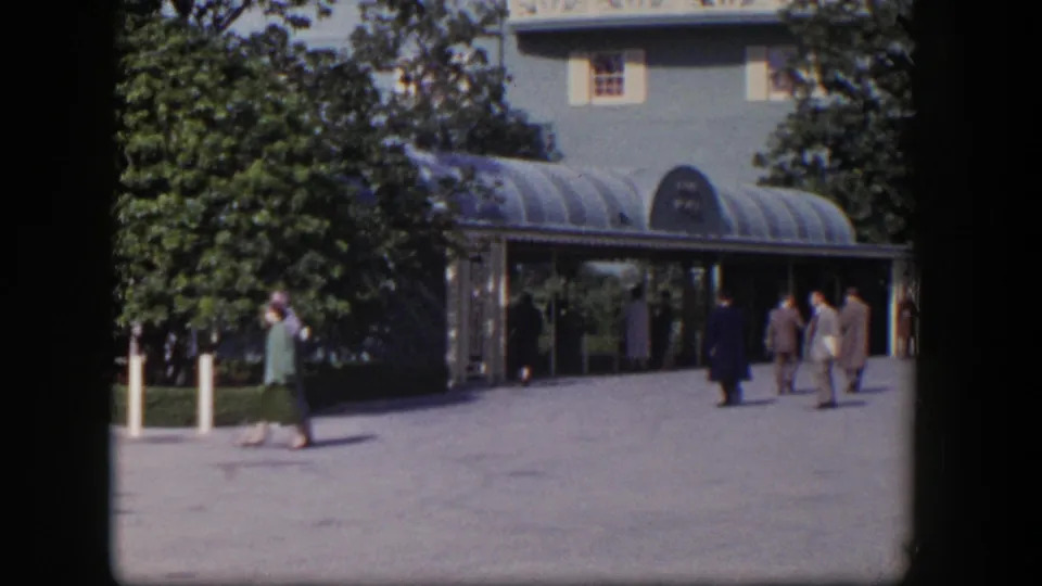 The final frame shows adults moving across the sunlit courtyard outside a 1954 Las Vegas building entrance with trees and a curved canopy.