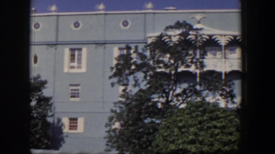 1954 Las Vegas home-movie frame showing circular hotel windows, white balcony trim, and foreground trees.