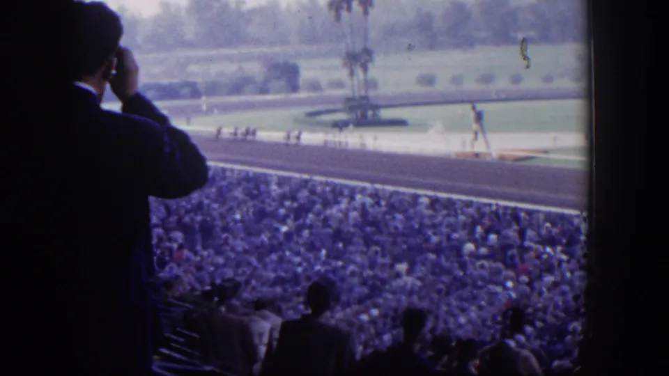 A 1954 Las Vegas horse-racing crowd fills the grandstands as a silhouetted spectator looks toward the track.