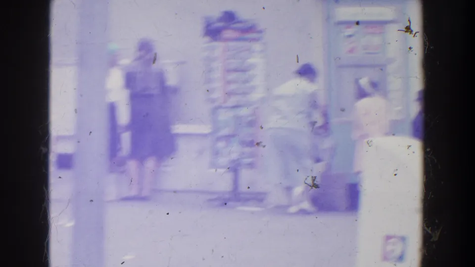 Indistinct people appear near a possible kiosk, signboard, or ticket area in the reported 1964 World's Fair home-movie footage.
