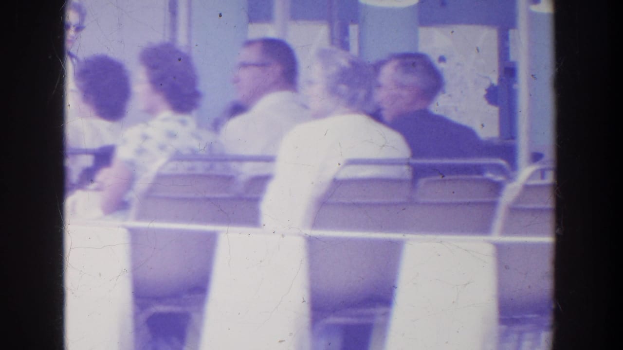 Adults ride an open tram, including several seated passengers seen in profile and from behind.