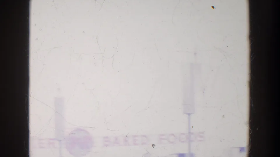 Faint BAKED FOODS text appears across the upper area of a bright pavilion view on grainy 8mm film.