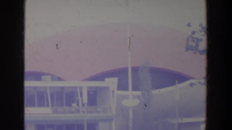 The pavilion's glass facade, curved pink-purple dome, slender pole, and sparse trees are visible in a faded 1964 World's Fair home-movie frame.