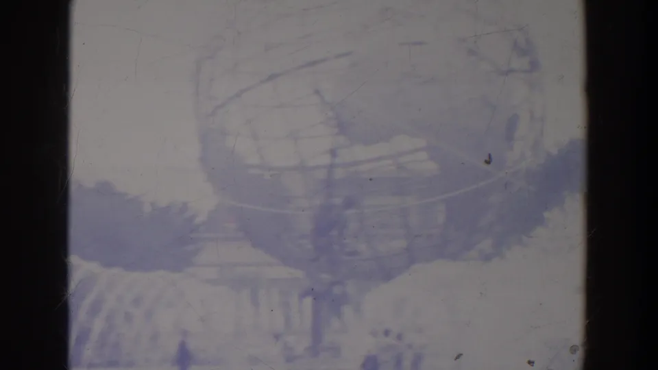 The Unisphere fills much of the frame, with fountain spray, trees, and distant visitors visible through faded purple-blue 8mm color.