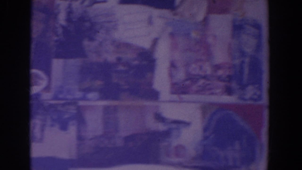 Aged 8mm frame showing poster-like graphics and architectural surfaces, likely from the described World's Fair home movie.